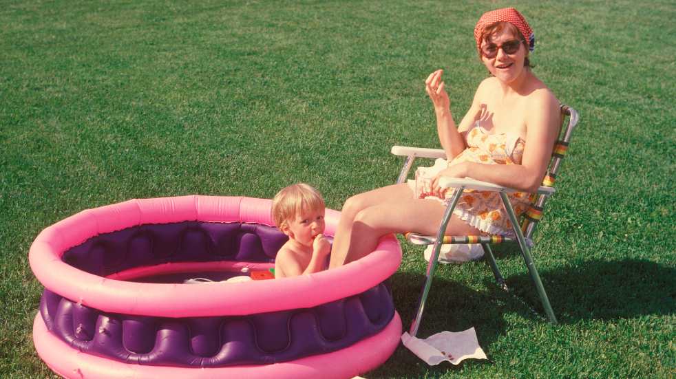 Child in paddling pool with mum 1970s